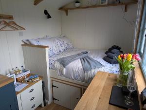 a small bedroom with a bed and a table with flowers at Cornish Valley Retreat in Bodmin