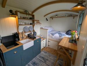 a kitchen with blue cabinets and a table and a bed at Cornish Valley Retreat in Bodmin
