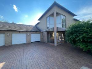 a house with two garage doors and a driveway at La Grace Guestrooms in Kroonstad