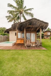 a house with a thatched roof and a deck with chairs at Pousada D'Oxum Caraíva in Caraíva +118 photos