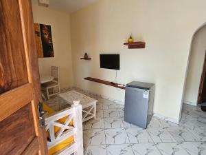 a room with a refrigerator and a tv on the wall at Orange apartments 3 in Watamu