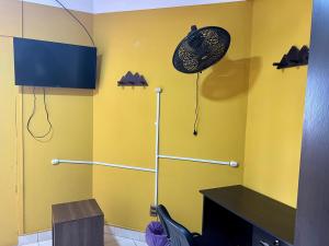 a room with a yellow wall with a fan at Hostal Urbano in Tarija +20 photos