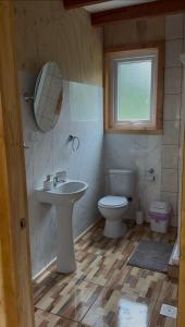a bathroom with a sink and a toilet and a mirror at Cabañas La Piedra del Queso in Melipeuco