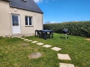 a table and chairs and a grill in a yard at O'Phare Ouest in Plouguerneau