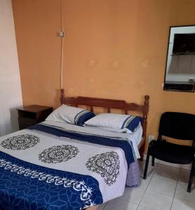 a bedroom with a bed with a blue and white blanket at Hostal Urbano in Tarija