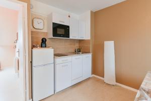 a kitchen with white cabinets and a white refrigerator at Cosy app near sea in Cabourg +10 photos