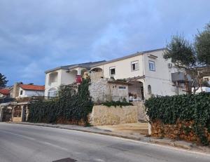 a white house on the side of a street at Apartmani Kasteljan 4, Stara Novalja in Stara Novalja