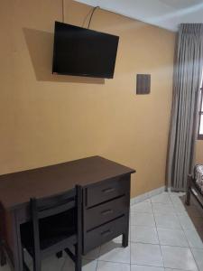 a room with a desk with a television on the wall at Hostal Urbano in Tarija