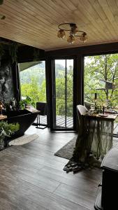 a room with a tub and a table and windows at Apart Garden з чаном-джакузі in Slavske