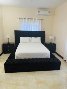 a bedroom with a large bed with a black bed frame at Trelawnys Bliss Escape in Spring Rises