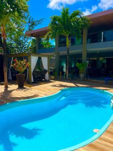 a swimming pool in front of a building with palm trees at Casa Brisa do Mar in Cabedelo