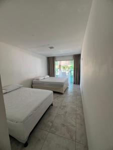 a bedroom with two beds and a hallway with a window at Casa Brisa do Mar in Cabedelo +40 photos