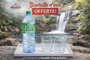 a bottle and two glasses on a tray with a waterfall at Résidence Senghor - THIÈS in Thiès