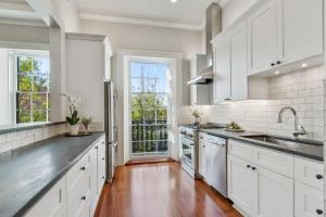 a kitchen with white cabinets and a large window at Historic CBD Townhomes with Courtyard in New Orleans