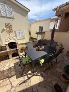 a black table and chairs on a patio with a fireplace at Holiday house Matej in Vir