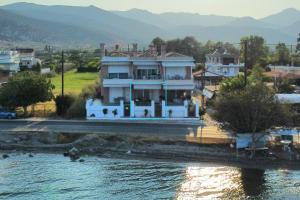 a large white house sitting on the side of a river at Blue Bay Suites in Myloi