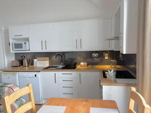 a kitchen with white cabinets and a wooden table at Woodlands Holiday Apartments in Lytham St Annes