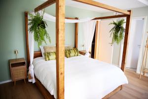 a bedroom with a four poster bed and two plants at Prime apartment in Liège