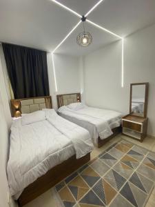 a bedroom with two beds and a mirror in it at سكن فندقى باكتوبر in Al Kawāmil Qiblī