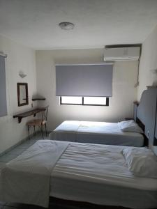 a hotel room with two beds and a desk at Invernadero Inn in Veracruz +17 photos