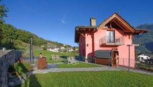 a pink house with a dog sitting in the yard at AFFITTACAMERE LA MAGIA DEI COLORI in Verrayes
