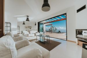 Una sala de estar con muebles blancos y vista al mar. en Ocean View Villa, en Funchal