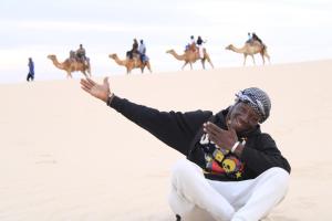 a woman sitting in the desert with a group of camels at Lompoul Nature in Tioukougne Peul