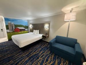 a hotel room with a bed and a blue chair at Travelodge by Wyndham Odessa in Odessa