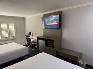 a hotel room with two beds and a flat screen tv at Travelodge by Wyndham Odessa in Odessa