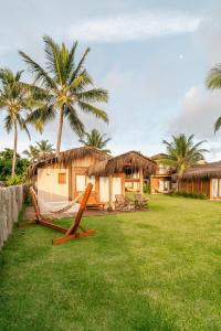 a resort with two lounge chairs and palm trees at Pousada D'Oxum Caraíva in Caraíva