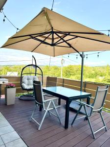 a table and chairs under an umbrella on a deck at ApartPodhale in Raba Wyżna
