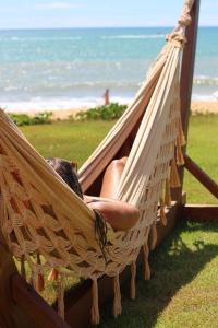 a person sitting in a hammock at the beach at Pousada D'Oxum Caraíva in Caraíva