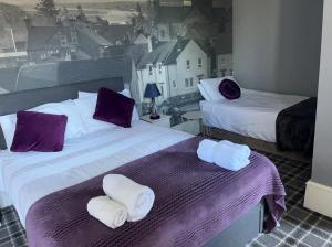 a hotel room with two beds with purple and white towels at Ugie House in Keith