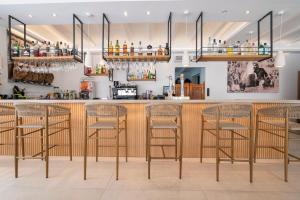 a bar with four bar stools in a room at Apartamentos Blanco Sol in Cala Vadella
