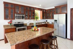 a kitchen with wooden cabinets and a granite counter top at Casa de Fox - Confort en medio de la jungla! in Manuel Antonio +27 photos