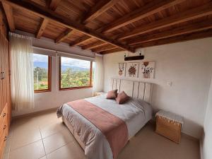 a bedroom with a bed and a large window at Cabaña Villa Serena in Villa de Leyva