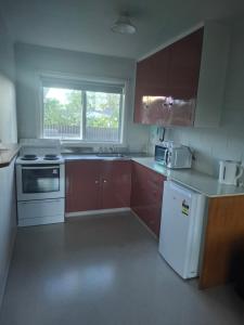 a kitchen with brown cabinets and white appliances at Aalton Motel Temuka in Temuka