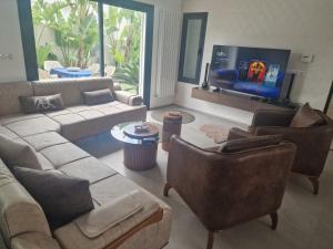 a living room with a couch and chairs and a tv at Villa janna in Sukrah
