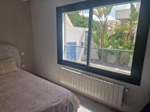 a bedroom with a bed and a window with a plant at Villa janna in Sukrah +23 photos