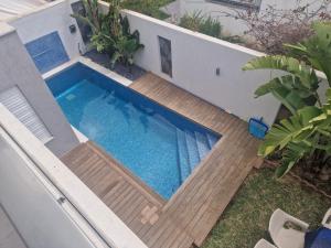 a swimming pool with a wooden deck next to a house at Villa janna in Sukrah