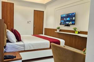 a hotel room with a bed and a television at TrueLife Nexus Suites in Tirupati