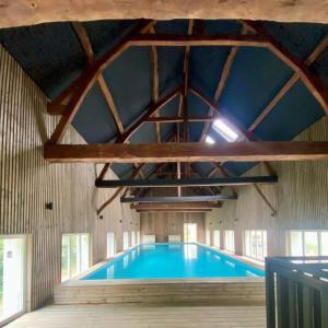 a swimming pool in a building with a ceiling at Logis cosy avec piscine in Saint-Josse