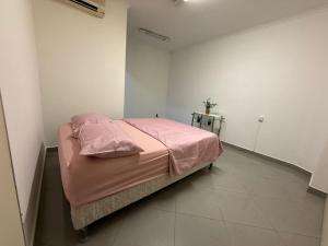 a bedroom with a bed with pink sheets and two tables at Hostel em SJC perto da rodoviária, centro,Embraer e cta in São José dos Campos