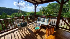 a porch with a swing and a chair and a table at Habitation Colas in Pointe-Noire