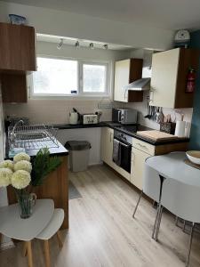 a kitchen with white cabinets and a table with a vase of flowers at The Retreat Camber in Camber