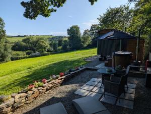 a garden with a table and chairs and an umbrella at Cornish Valley Retreat in Bodmin