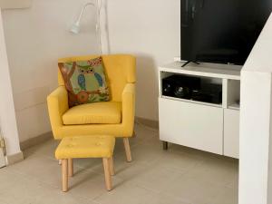 a yellow chair with a pillow sitting next to a tv at The Town House - Mojacar in Mojácar