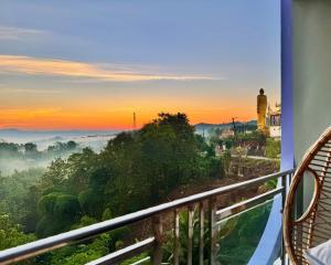 a man standing on a balcony looking out at a foggy sunrise at Cloudy Inn Resort in Bāndarban