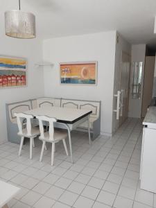 a dining room with a table and white chairs at Pointe Saint-Jacques - L'entre deux vagues in Sarzeau