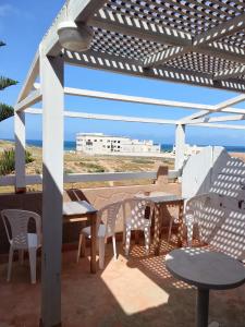 a patio with tables and chairs and a view of the beach at Tildi surf house in Imsouane